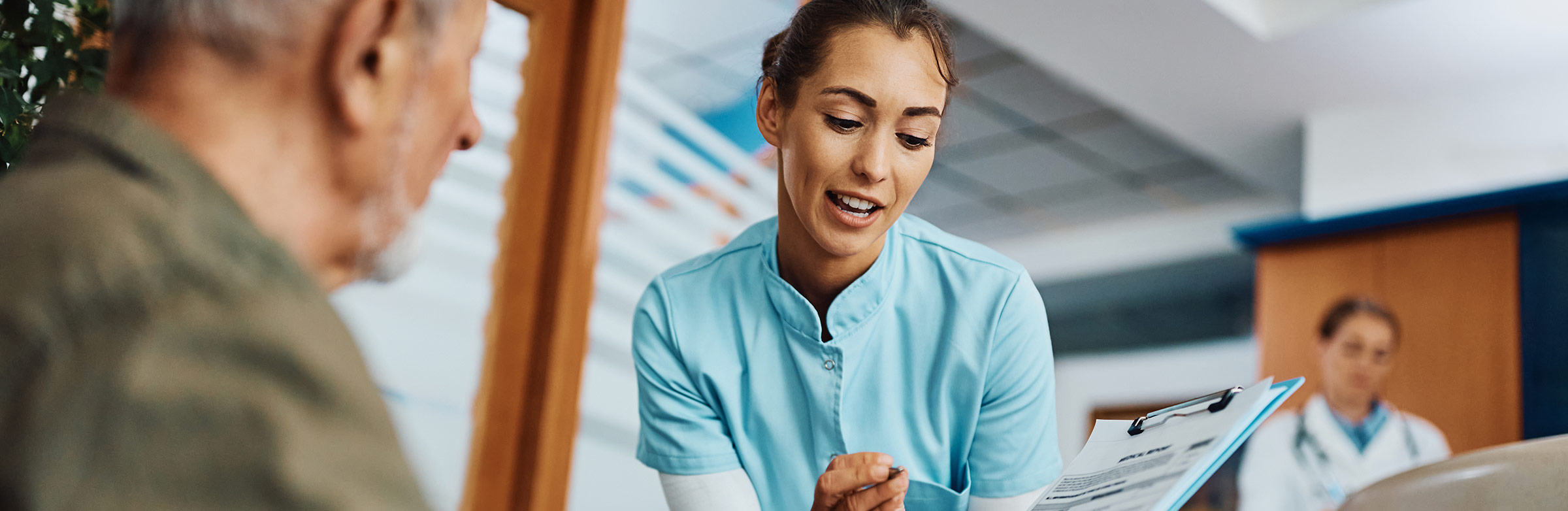 Image of a medical office assistant helping a patient with paperwork