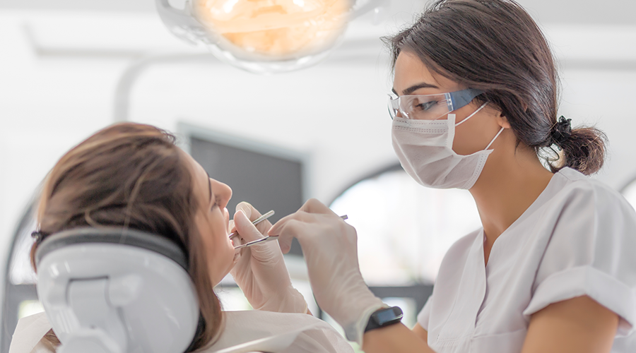 a female dentist cleaning teeth for a patient